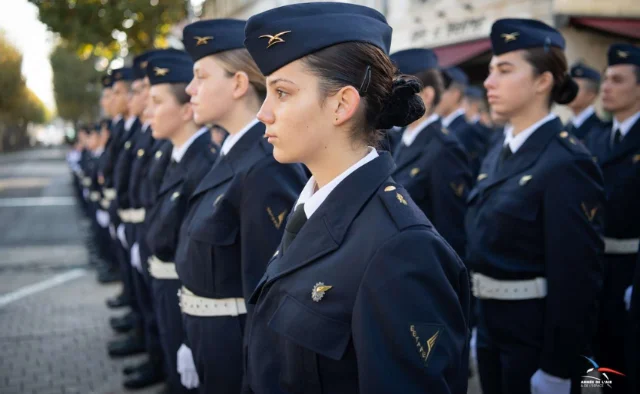 Armée de l'Air en uniforme bleu marine, formant une ligne droite, casquettes sur la tête et insignes sur les vestes.